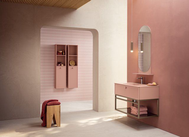 Un bagno con pareti rosa, mobili rosa, un lavandino e uno specchio.