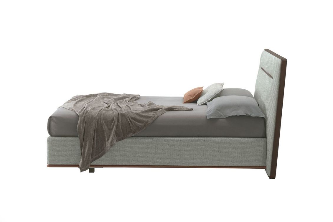 Un letto con una coperta e dei cuscini su uno sfondo bianco.