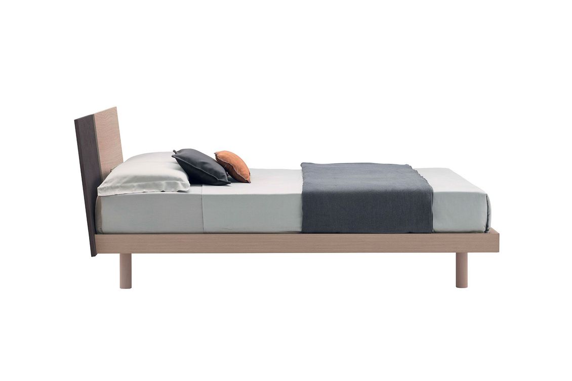Un letto con materasso e cuscini su uno sfondo bianco.