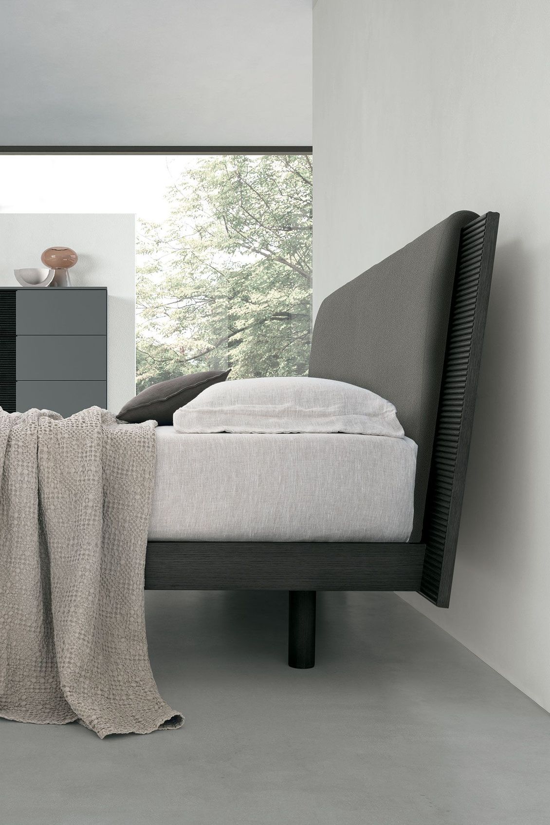 Un letto con una coperta in una camera da letto vicino a una finestra.