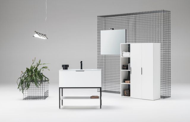 Un bagno con lavandino, specchio, armadietti e una pianta.