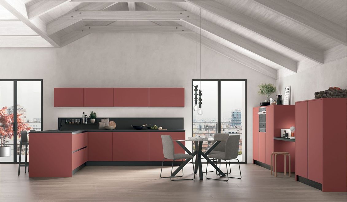 Una cucina con mobili rossi, tavolo e sedie.