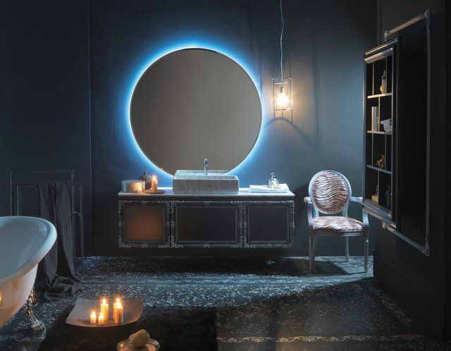 Un bagno con uno specchio rotondo e una vasca da bagno
