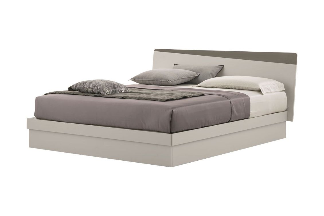 Un letto con un piumone grigio e cuscini su uno sfondo bianco.
