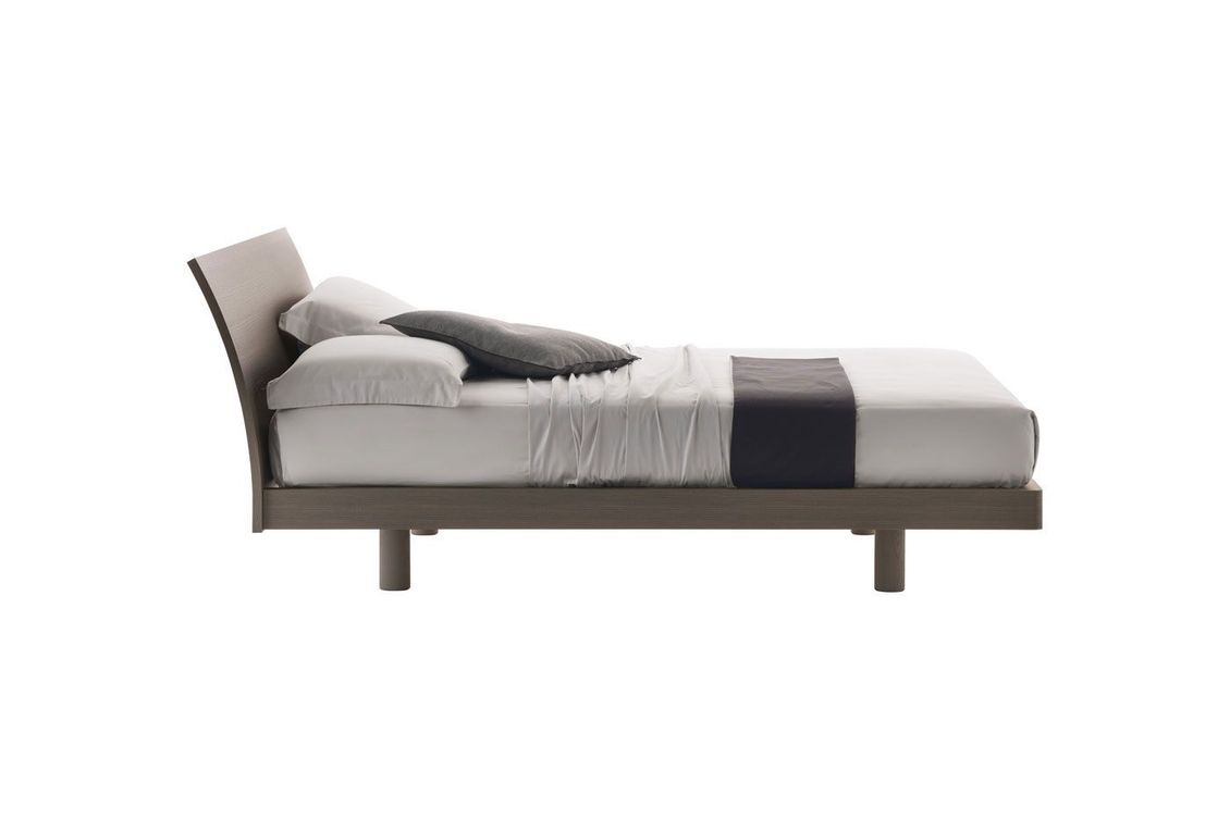 Un letto con lenzuola e cuscini bianchi su uno sfondo bianco.