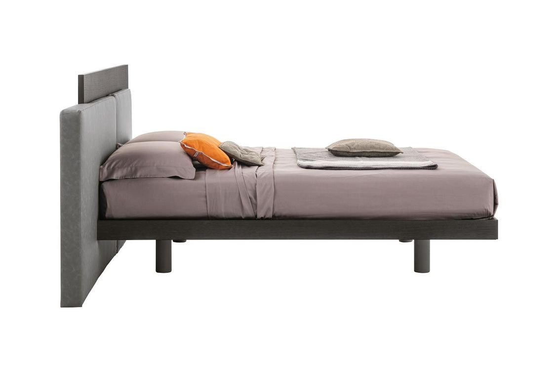 Un letto con testiera e cuscini su uno sfondo bianco.