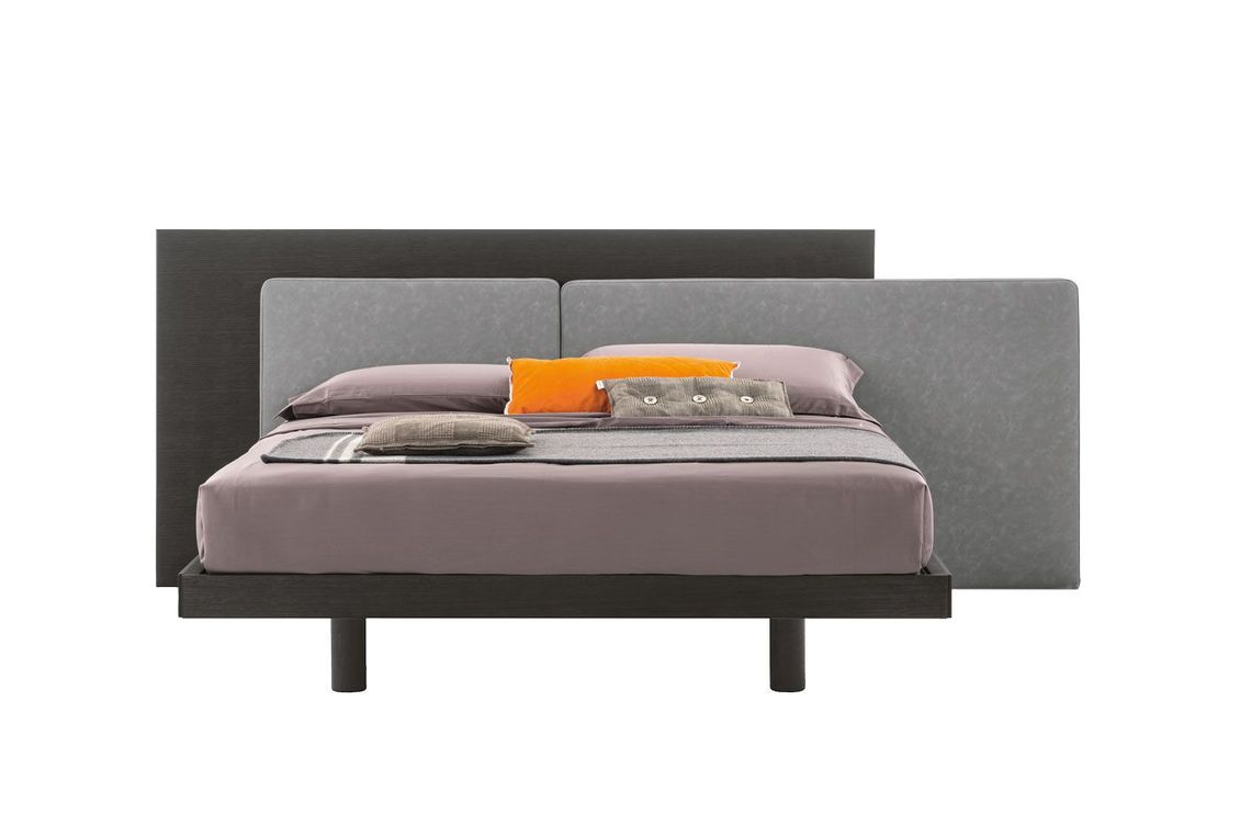 Un letto con testiera e cuscini su uno sfondo bianco.