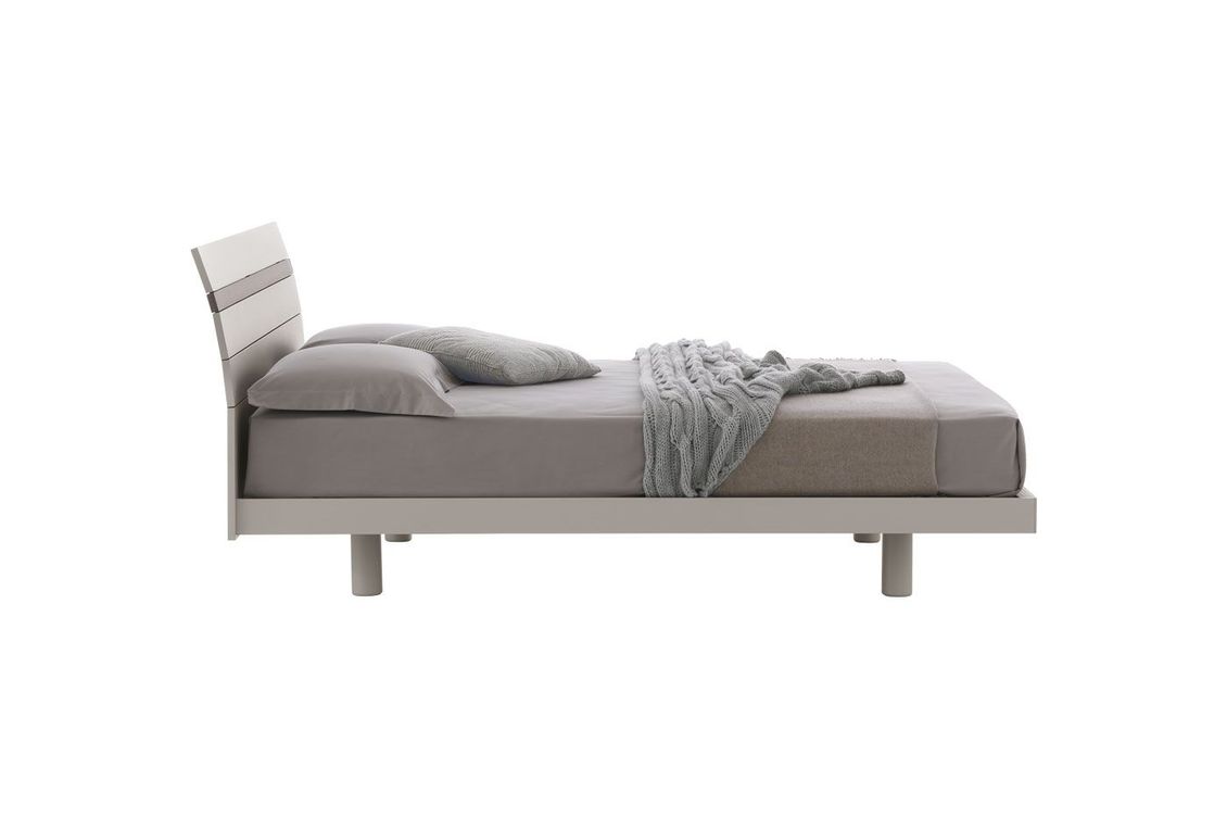 Un letto con una coperta e dei cuscini su uno sfondo bianco.