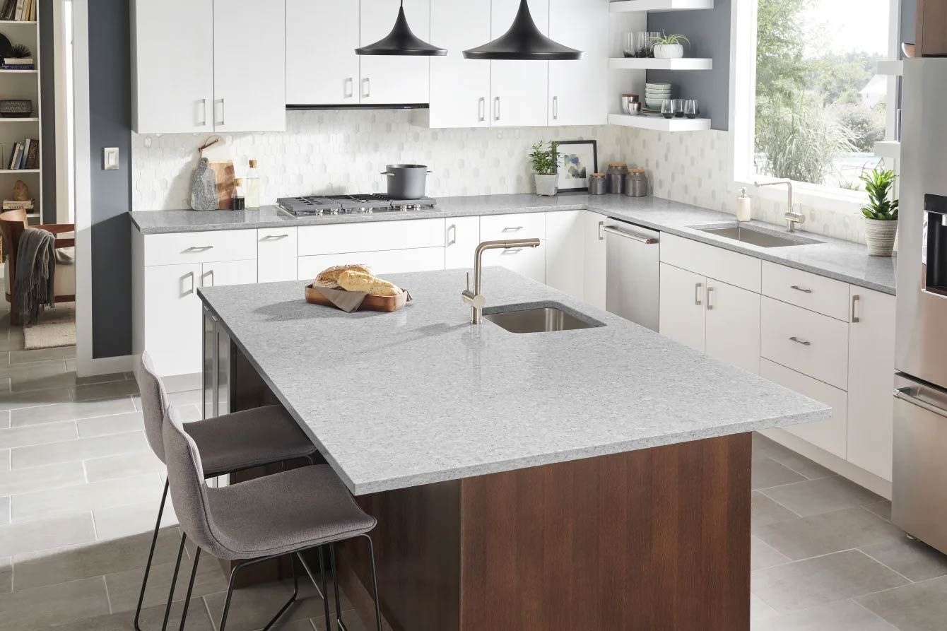 Modern kitchen with island, white cabinets, gray countertops, and stainless steel appliances.