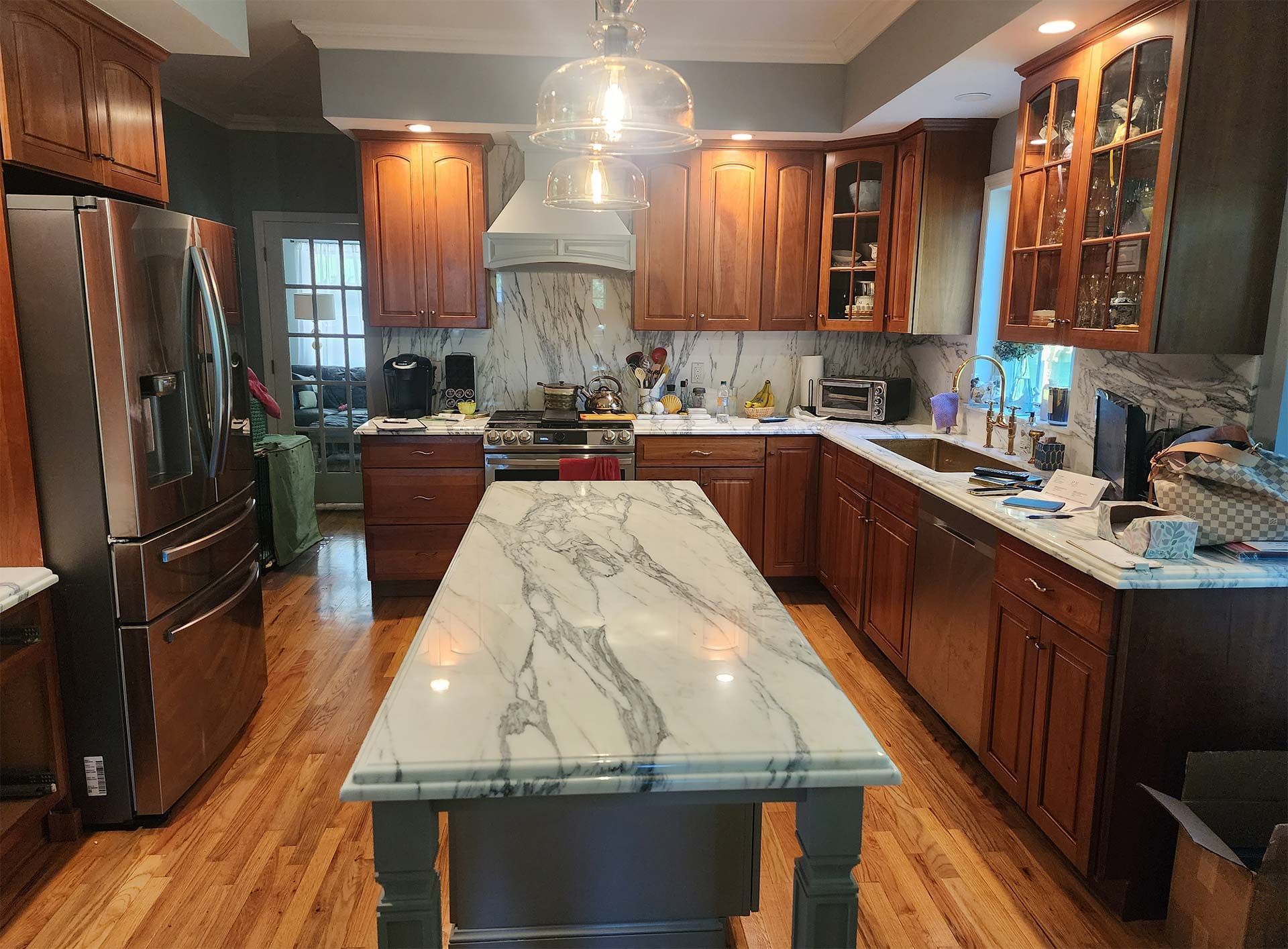 Kitchen with wooden cabinets, island with marble countertop, stainless steel appliances, and a range.