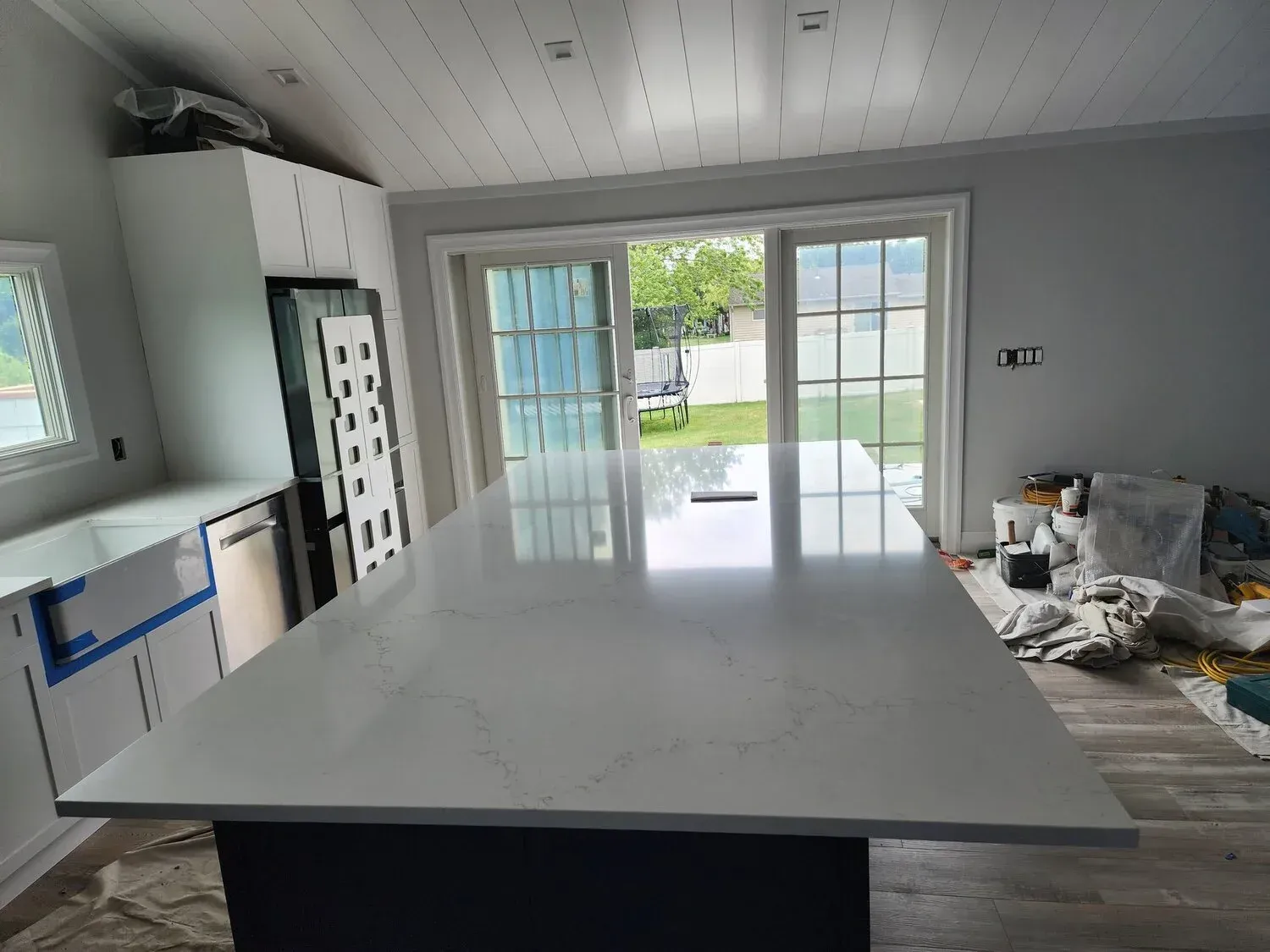 Modern kitchen with a large white island, a sliding door, and a backyard view.