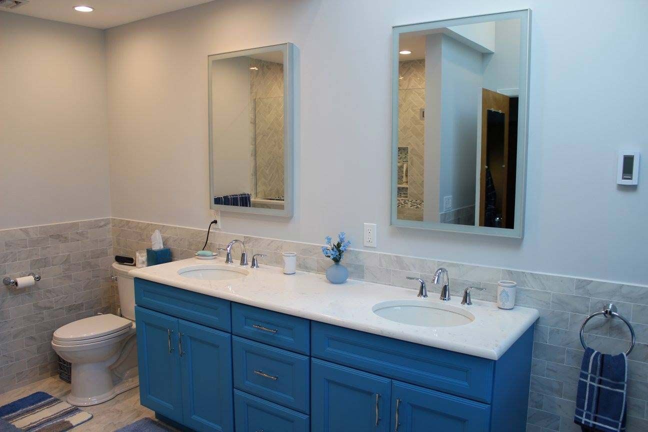 Blue double vanity bathroom with mirrors and toilet.