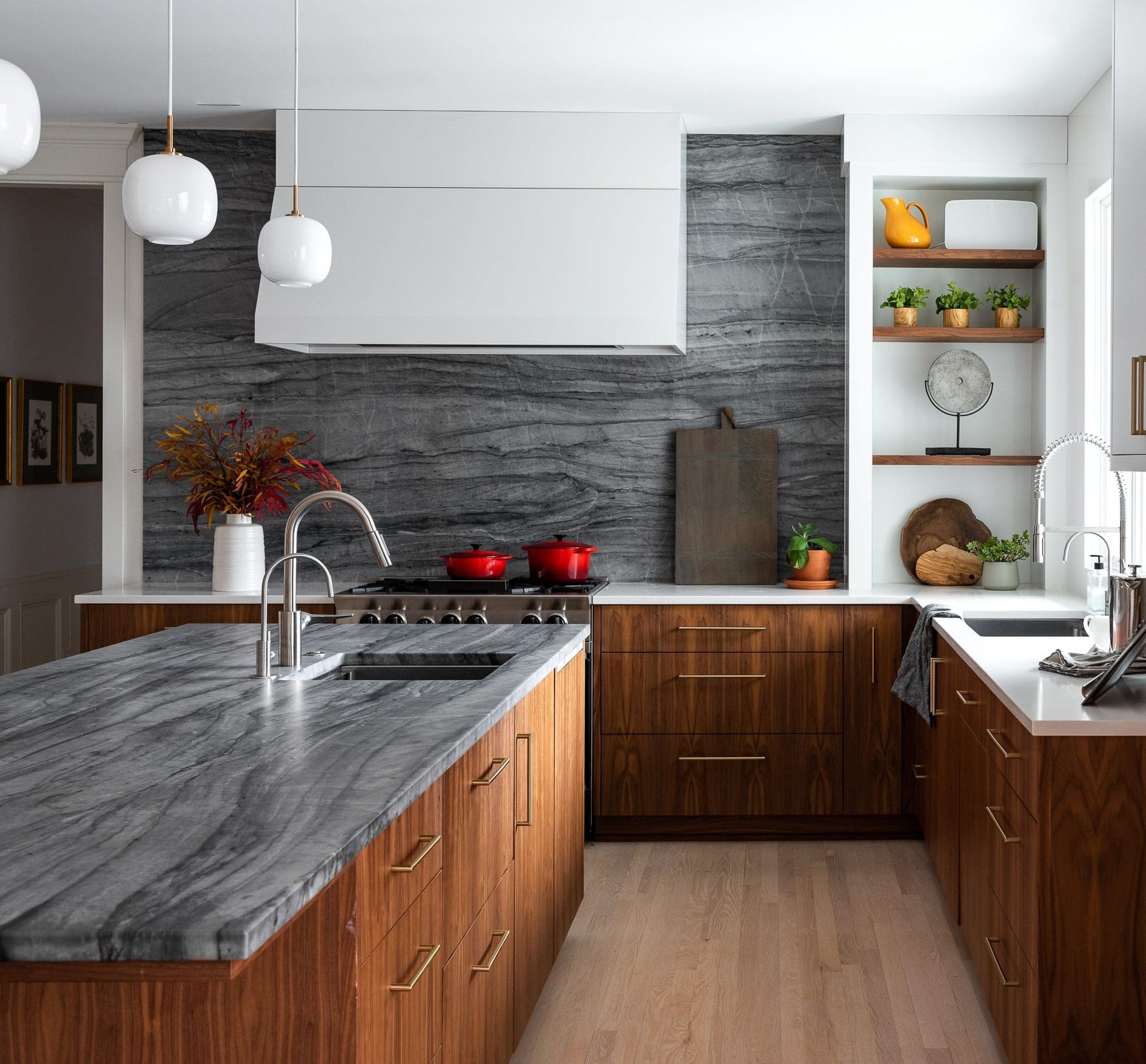 Modern kitchen with gray stone counters, wood cabinets, and pendant lights