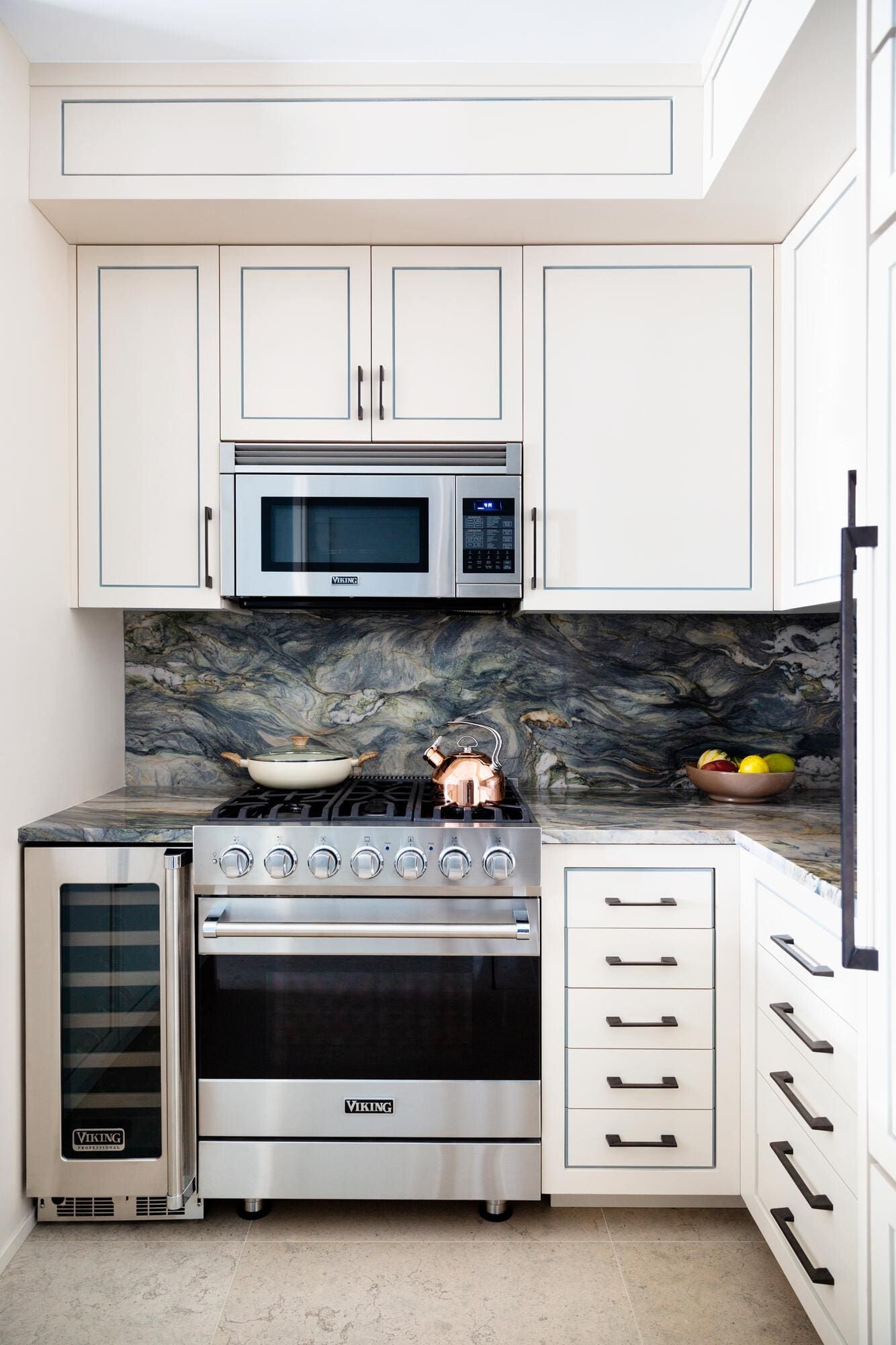 Modern white kitchen with stainless steel appliances, marble backsplash, and black countertop