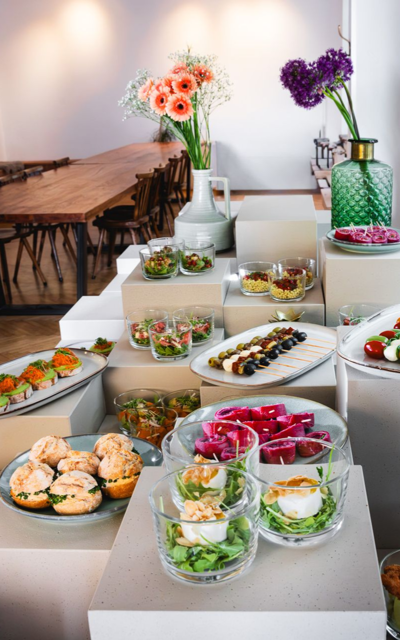 Buffet mit verschiedenen Vorspeisen, Salaten und Blumen in einem hellen Speisesaal