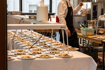 Buffet mit vielen angerichteten Speisen und einem Kellner in einer Restaurantküche