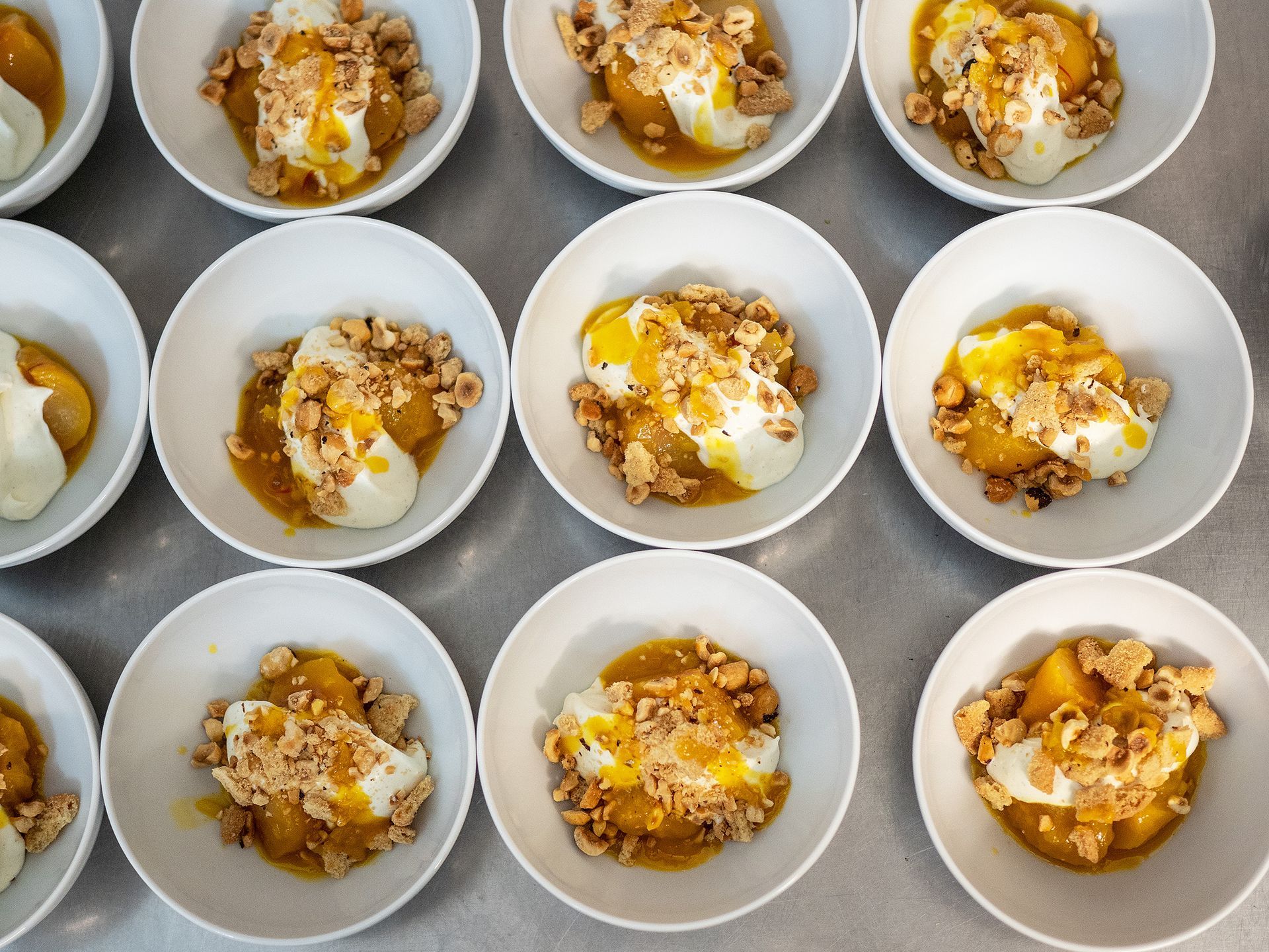 Schüsseln mit Dessert, garniert mit Sahne und Granola, in einem Gitter angeordnet.