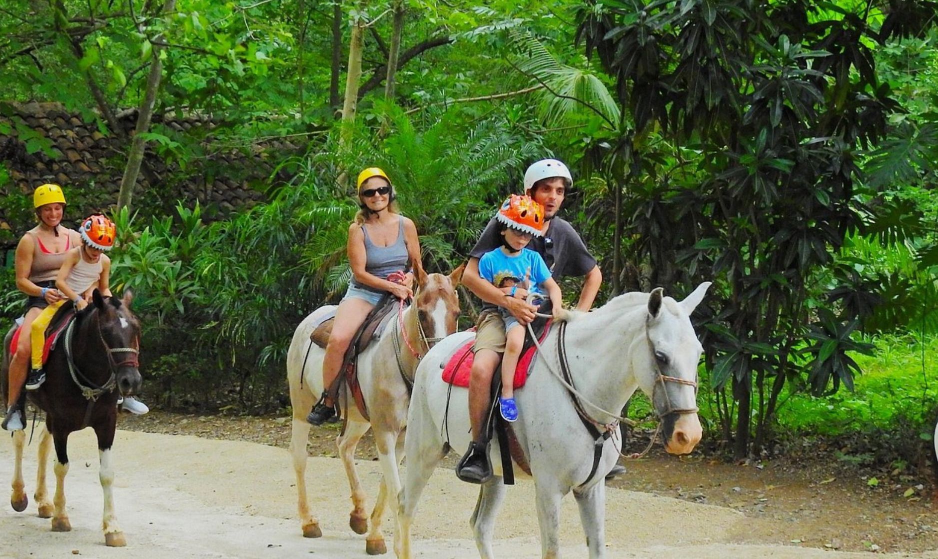 Family enjoying a horseback riding excursion in Costa Rica surrounded by lush tropical vegetation and natural scenery