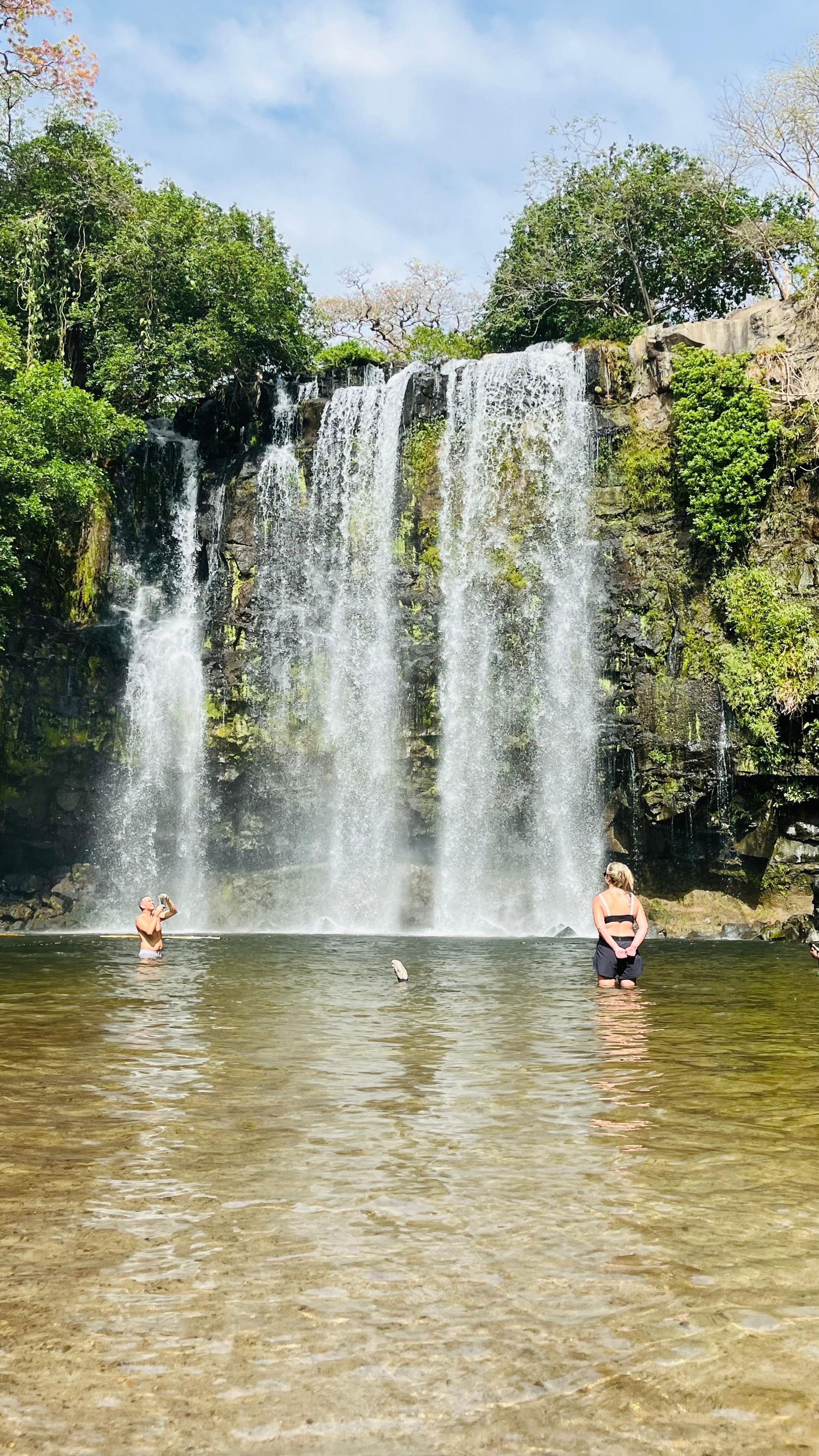 Visitors enjoying Llanos de Cortés Waterfall surrounded by tropical dry forest in Guanacaste, Costa 