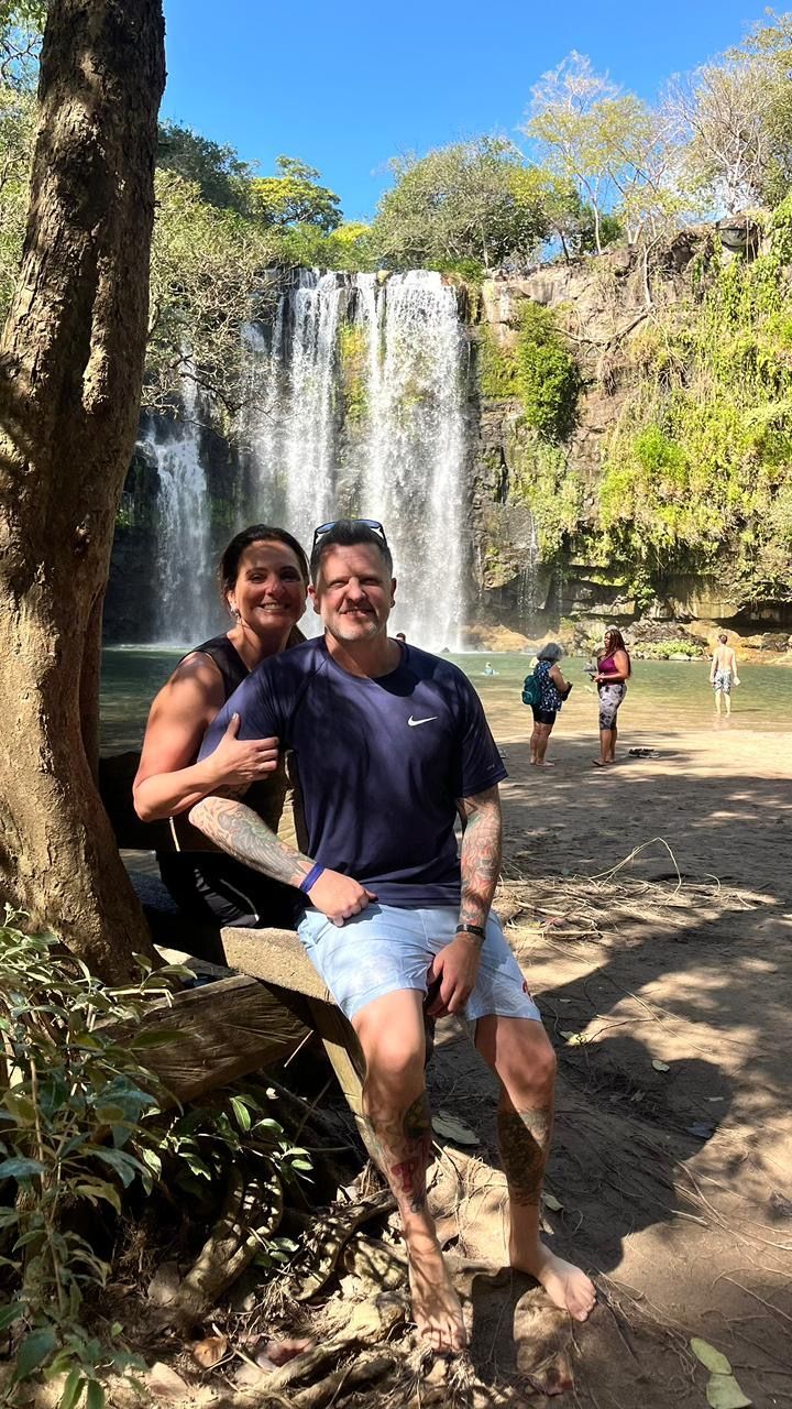 Couple visiting Llanos de Cortés Waterfall in Guanacaste, Costa Rica.
