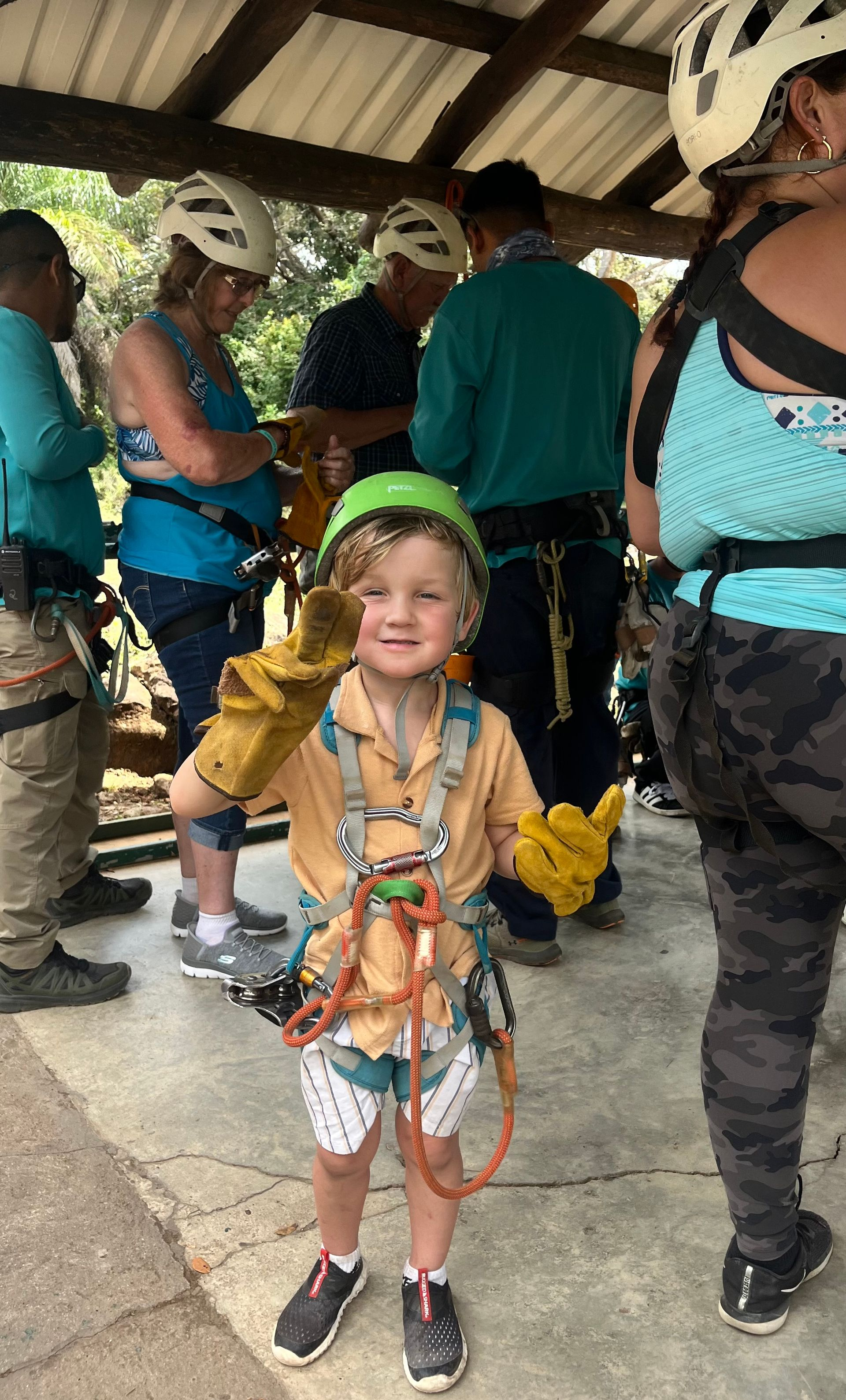 Young child wearing a helmet and safety harness for a family zipline adventure in Costa Rica
