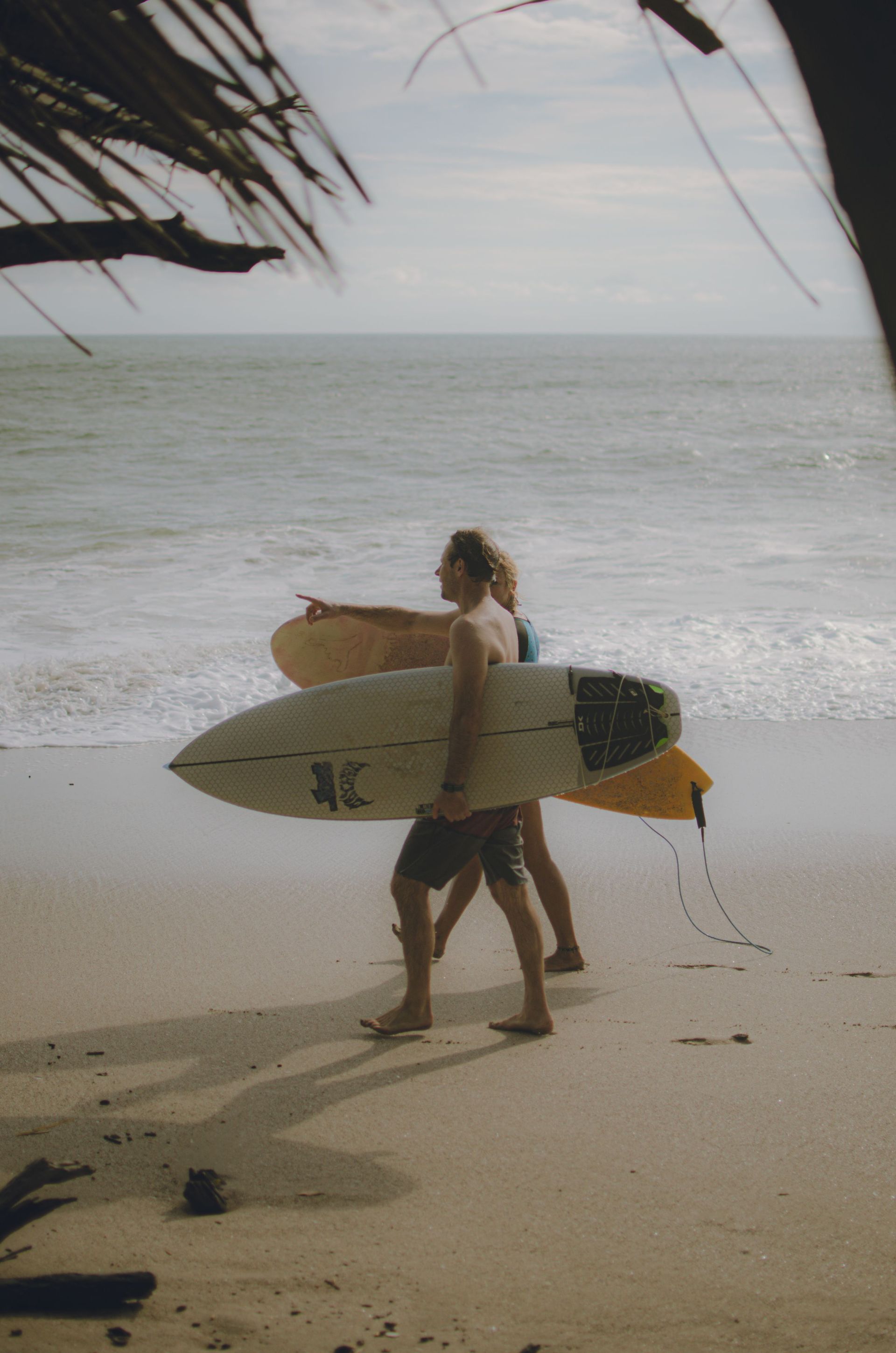 Surfer walking on Tamarindo beach during a surfing experience on the Pacific coast of Costa Rica.