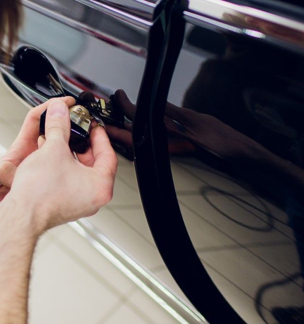 A Person Is Opening a Car Door with A Key — Tropical Locksmiths in Cannonvale, QLD