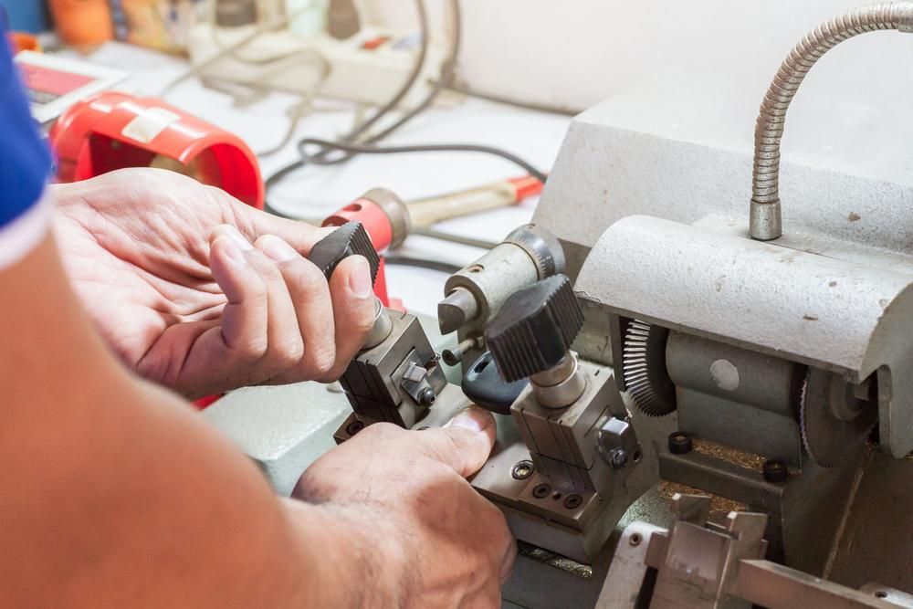 A Person Is Cutting a Key with A Machine — Tropical Locksmiths in Airlie Beach, QLD