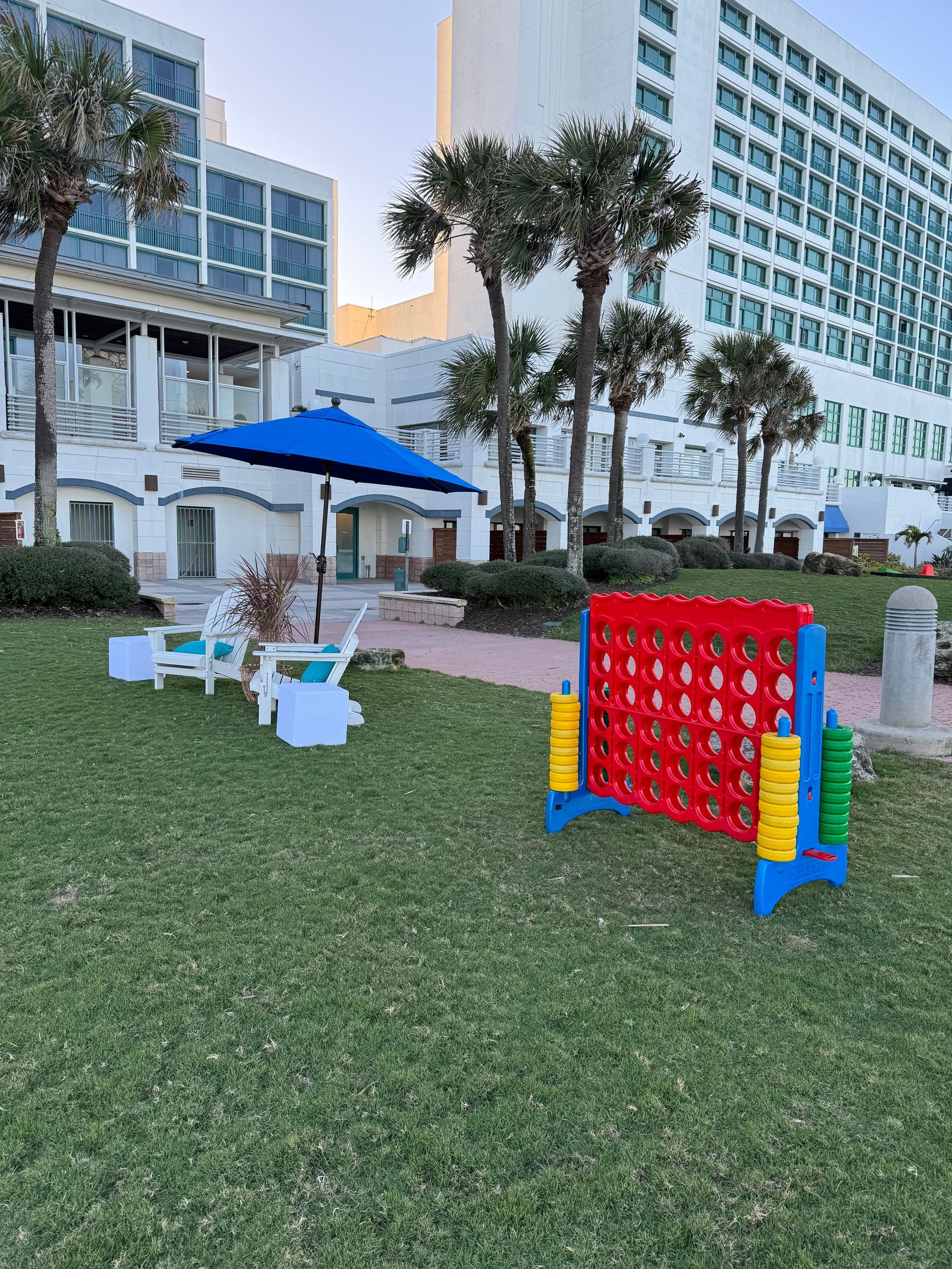 White beach themed adirondack chairs with blue pillows and blue umbrella giant connect four