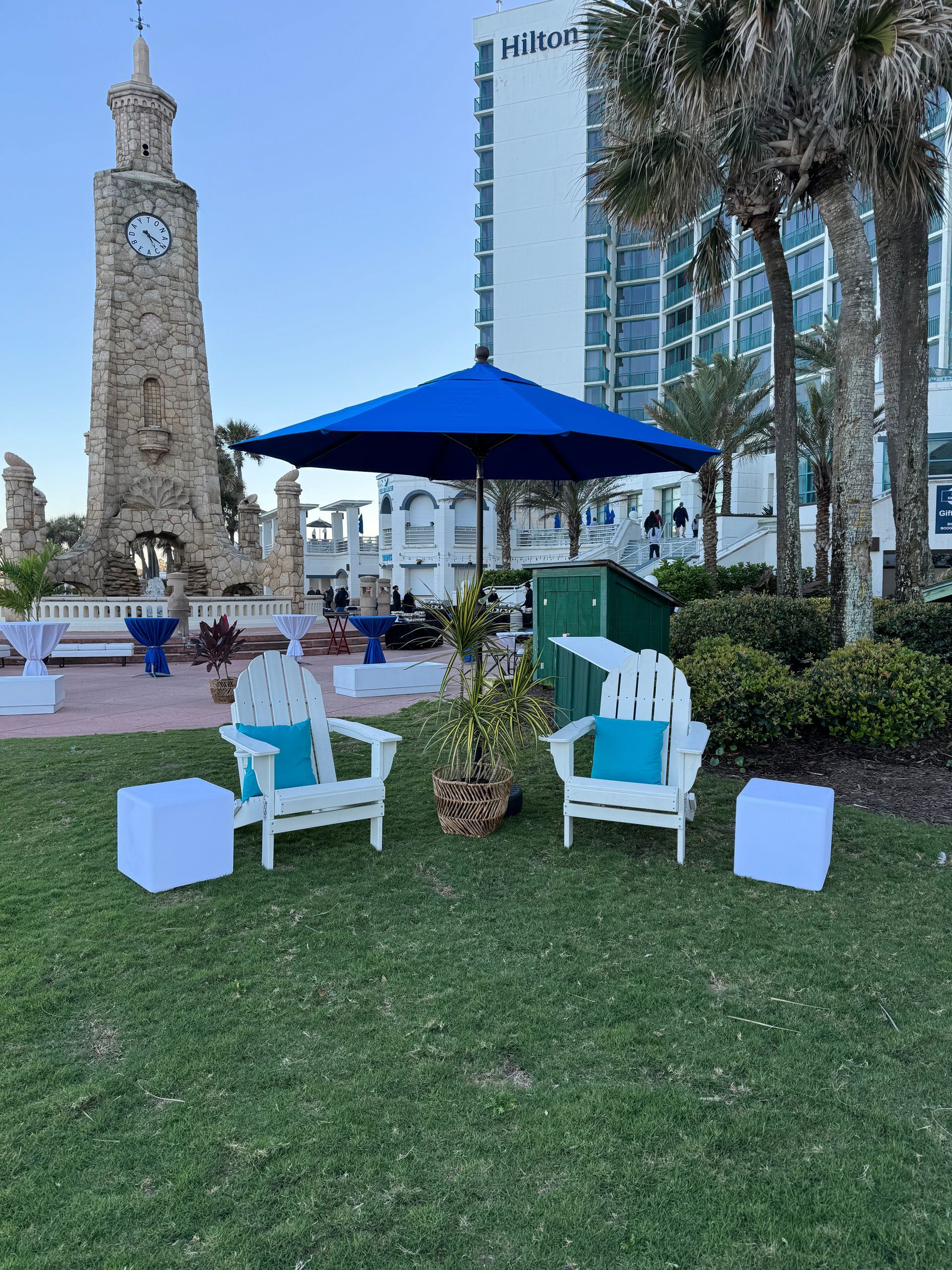 White beach themed adirondack chairs with blue pillows and blue umbrella