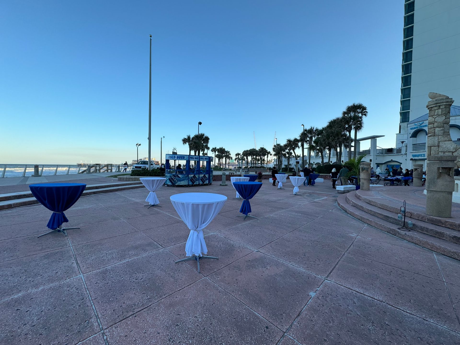 Blue and white hightop tables , white benches with a dj at a beach themed event 