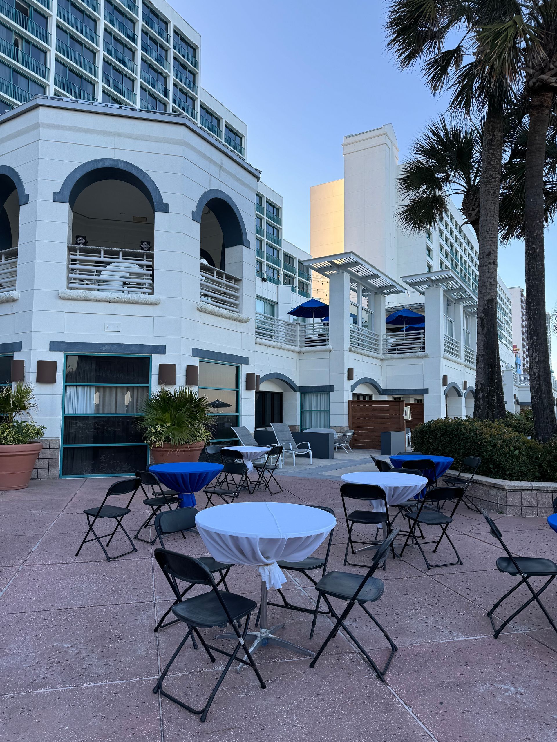 Blue and white hightop tables, white benches with a dj at a beach themed event 