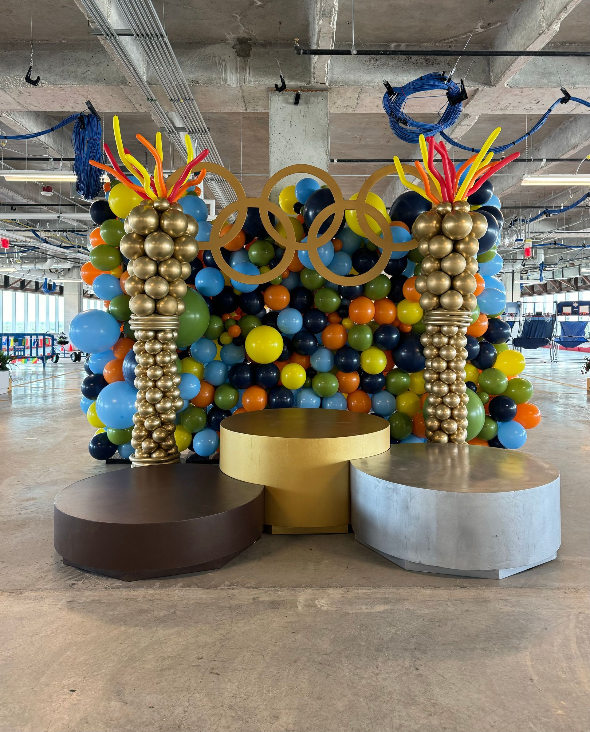 gold silver and bronze podiums indoor with balloons for a olympic themed event