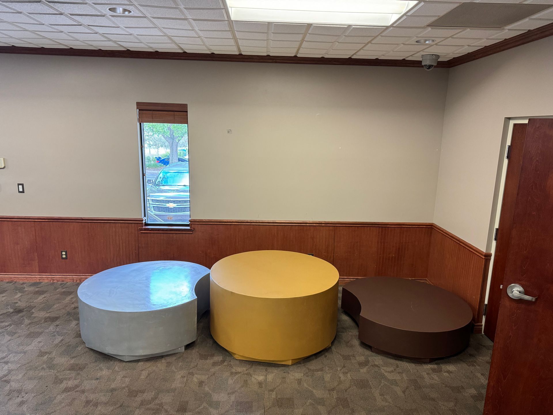 Indoor setup featuring three Olympic-style podiums in gold, silver, and bronze, placed against a beige wall.