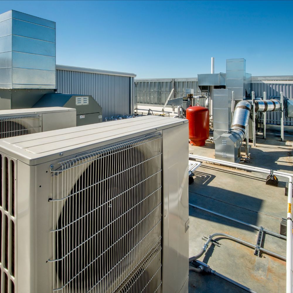 Overview of a commercial rooftop HVAC system showing ductwork and a red expansion tank.