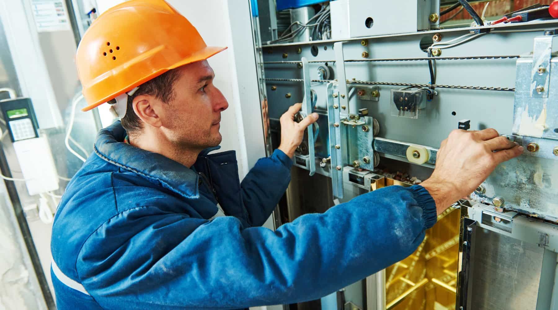 Worker in orange hard hat inspecting machinery inside an industrial plant