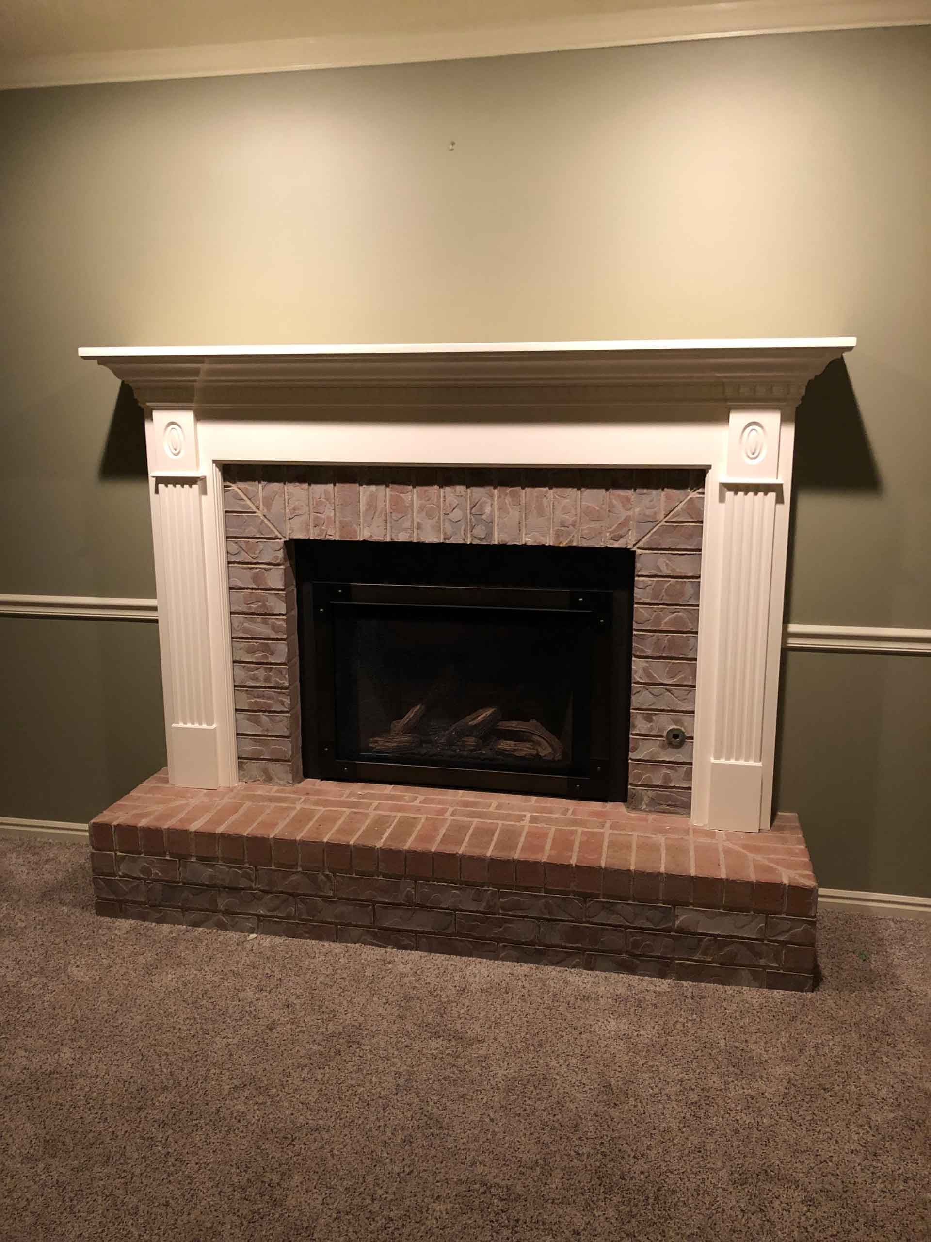 A brick fireplace with a white mantle in a living room.