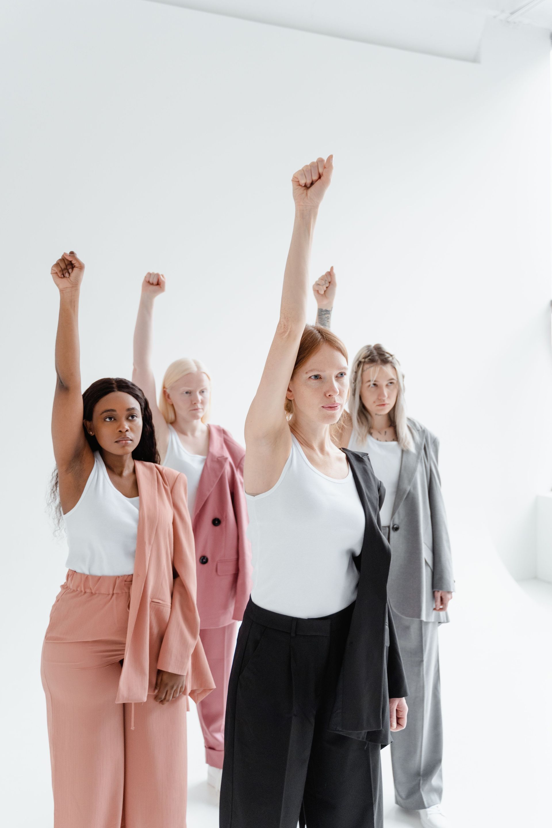 Four people in a bright studio raising fists in the air during an exercise or group activity