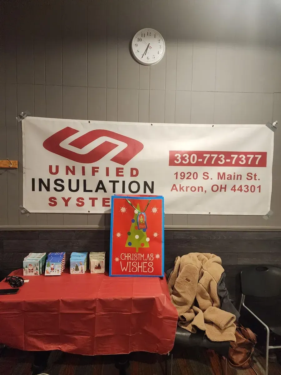Red and white Unified Insulation Systems banner above a table with gifts and a red display board.