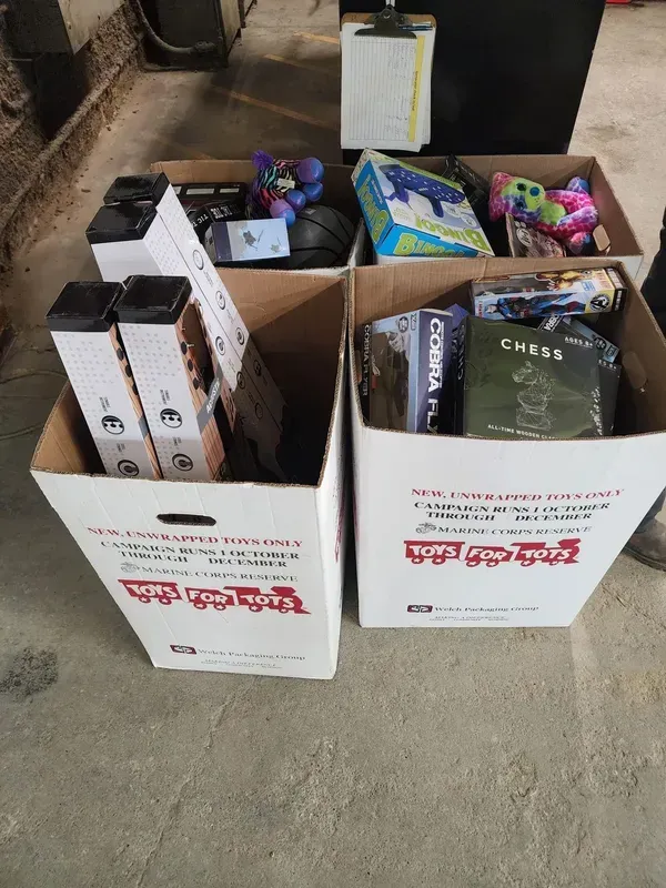 Two cardboard boxes filled with assorted packaged goods on a concrete floor.