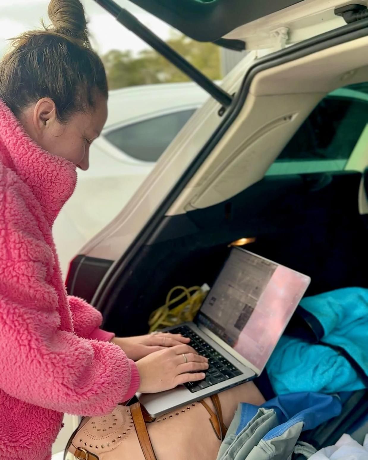 A Woman is Typing on a Laptop in the Back of a Car — Gem Socials In Port Macquarie, NSW