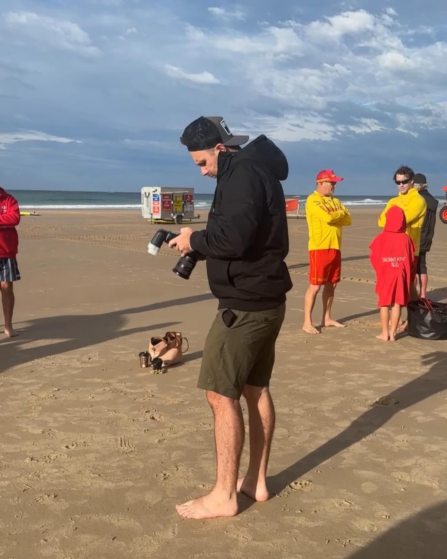 A Man is Standing on a Beach Holding a Camera — Gem Socials In Port Macquarie, NSW