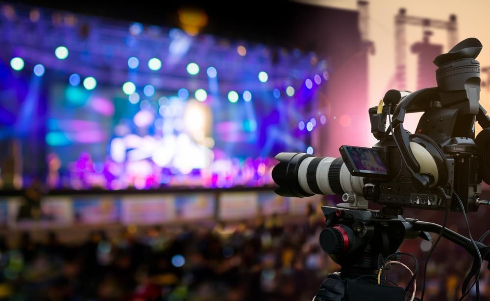 A Person is Holding a Camera in Front of a Stage at a Concert — Gem Socials In Port Macquarie, NSW