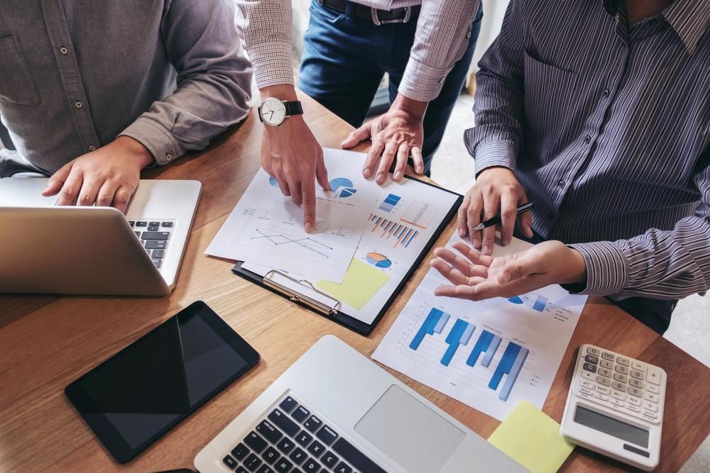 A Group of Men Are Sitting at a Table With Laptops and Papers — Gem Socials In Port Macquarie, NSW