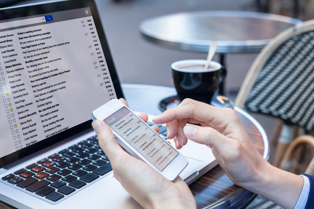 A Person is Using a Cell Phone in Front of a Laptop Computer — Gem Socials In Port Macquarie, NSW