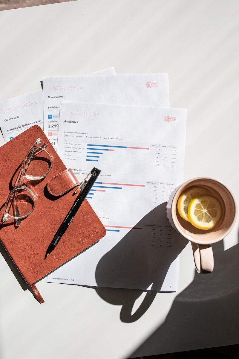 A cup of tea with a slice of lemon is on a table next to a notebook and glasses — Gem Socials In Port Macquarie, NSW