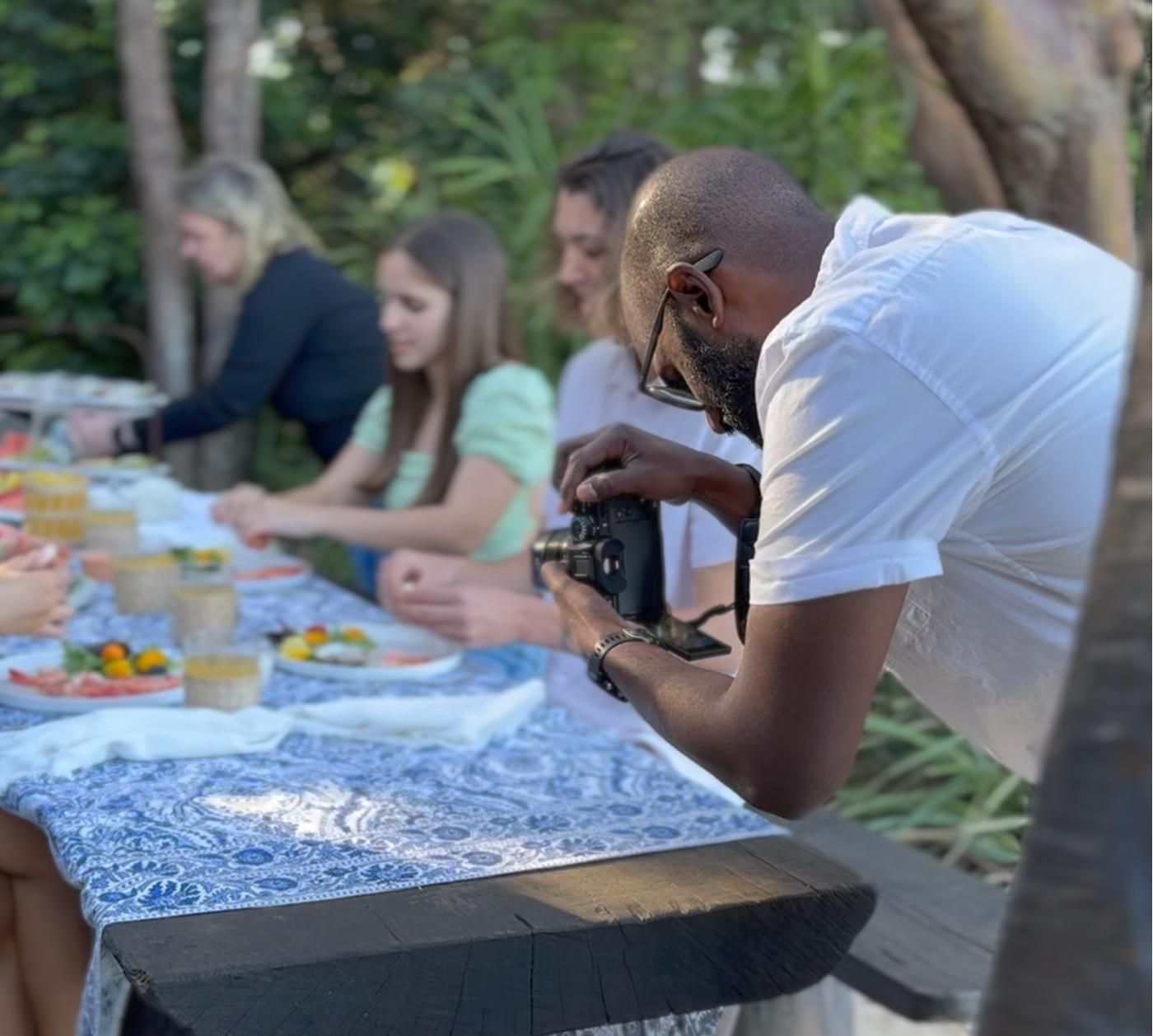 A Man is Taking a Picture of a Group of People Sitting at a Table — Gem Socials In Laurieton, NSW