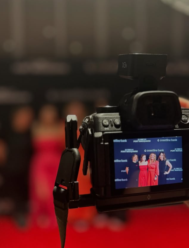 A camera is taking a picture of a group of people — Gem Socials In Port Macquarie, NSW