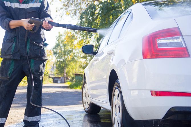 a man cleaning a car in front of a customers home in phoenix arizona