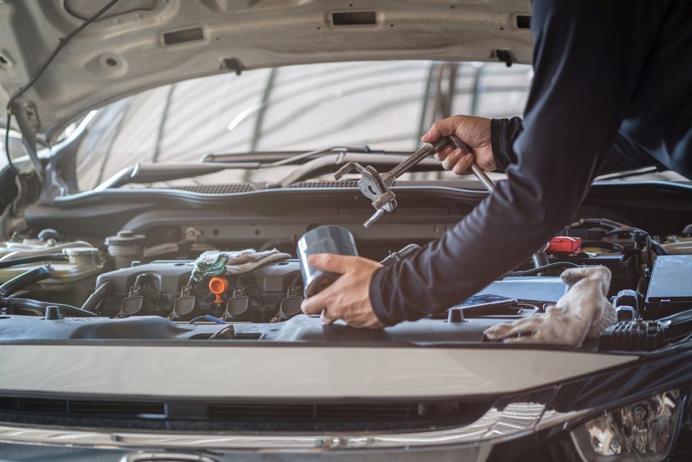 A Man Is Working On The Engine Of A Car With A Wrench — East Lismore Automotive in  East Lismore, NSW